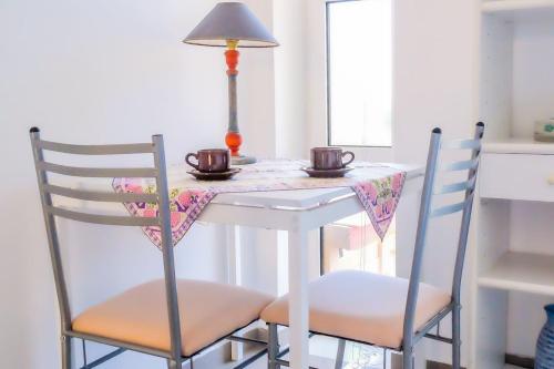 a white table with two chairs and two cups on it at Seaview Studio in Gázion