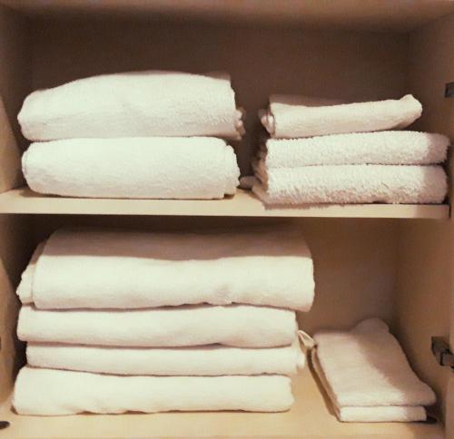 ein Schrank mit weißen Handtüchern auf einem Regal in der Unterkunft white holiday house in Desenzano del Garda