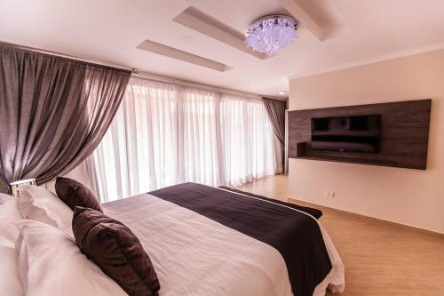 a bedroom with a bed with a television and a chandelier at Foz Plaza Hotel in Foz do Iguaçu