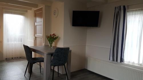 mesa de comedor con 2 sillas y TV en la pared en Vakantiewoning met terras vlakbij strand en centrum en Zoutelande