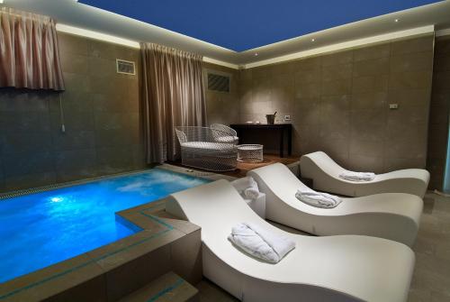 Habitación con piscina con sillas blancas. en Hotel Atlantic & Spa, en Gabicce Mare
