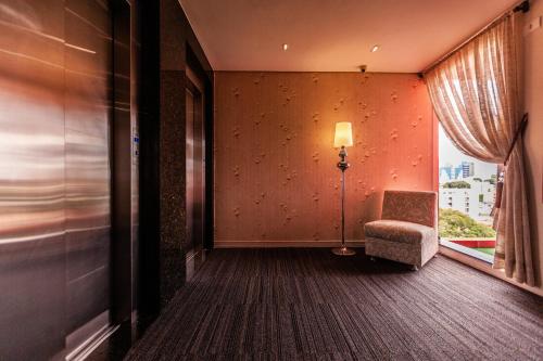 a room with a chair and a lamp and a window at Foz Plaza Hotel in Foz do Iguaçu