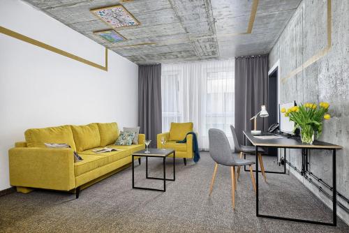a living room with a yellow couch and a table at Hotel Arche Geologiczna in Warsaw