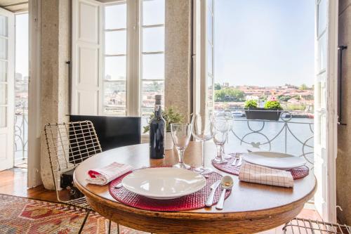 a table with plates and wine glasses in a room with a window at Porto Premium River View II in Porto