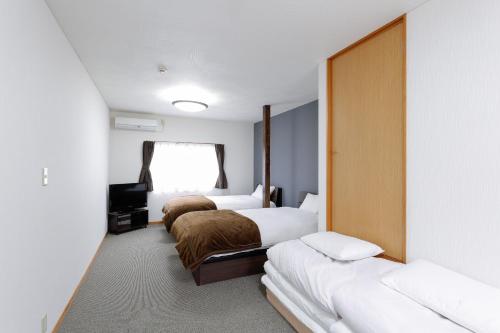 um quarto de hotel com três camas e uma janela em Hummingbird Kanazawa em Kanazawa