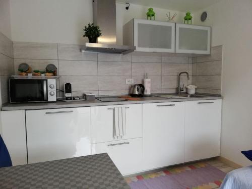 a kitchen with white cabinets and a microwave at Appartamento Le Magnolie 2 in Mestre