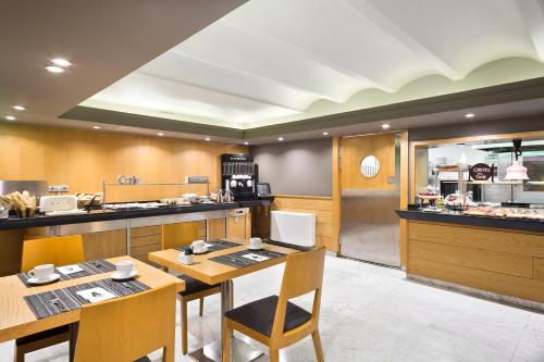 a restaurant with wooden tables and chairs and a kitchen at Acta Atrium Palace in Barcelona