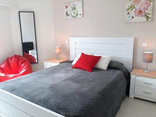 a bedroom with a large bed with a red pillow at ABMAR- Por-do-sol, Vista mar, Remodelado, Wifi, 80mt Praia in Quarteira