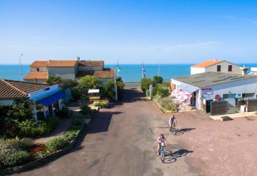 two people riding bikes down a road near the ocean at Camping Le Puits de l'Auture in Saint-Palais-sur-Mer