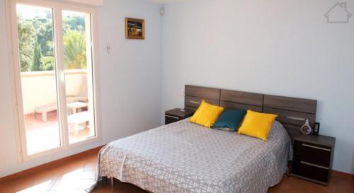 a bedroom with a bed with yellow and blue pillows at Villa 47 Hameau des Greens in Sainte-Maxime