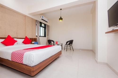 a bedroom with a bed with red pillows and a tv at Hotel Park Inn in Vasai