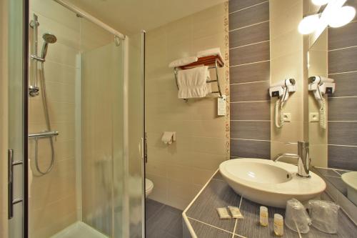 een badkamer met een wastafel en een douche bij Hôtel Le Madrigal in Sarlat-la-Canéda