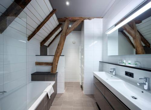 a bathroom with two sinks and a bath tub at Hotel Winselerhof by Flow in Landgraaf
