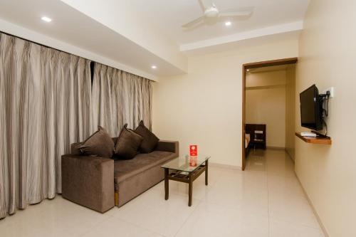 a living room with a couch and a table and a television at Hotel Park Inn in Vasai
