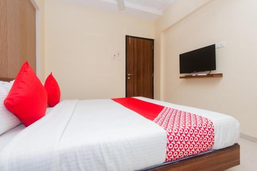 a bedroom with a bed with red pillows and a television at Hotel Park Inn in Vasai