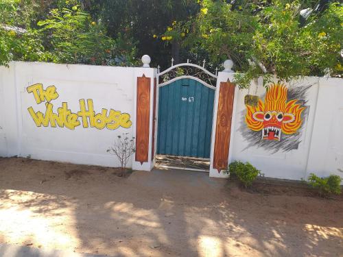 a white fence with a gate with a painting on it at The White House in Trincomalee