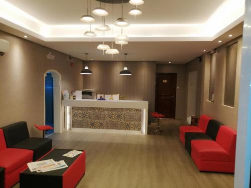 a waiting room with red couches and a counter at Sun City Hotel in Muscat