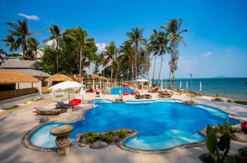 a pool at a resort with palm trees and the ocean at Villa Cha-Cha Krabi Beachfront Resort in Ao Nam Mao