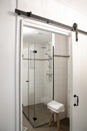a glass shower door with a stool in a bathroom at Het Ankertje (Oosterhaven) in Medemblik