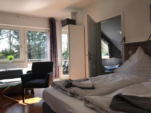 a bedroom with a bed and a chair and windows at Wohnen am Wanderweg in Aurich