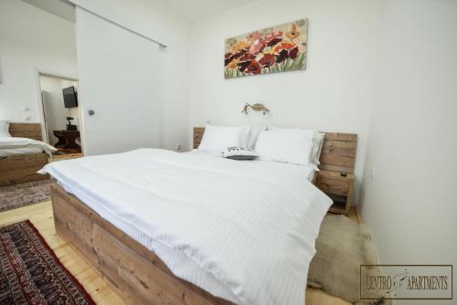 a bedroom with a large bed with white sheets at Centro Apartments in Sremska Mitrovica