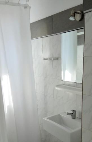 a white bathroom with a sink and a mirror at Nicos Studios & Apartments in Logaras