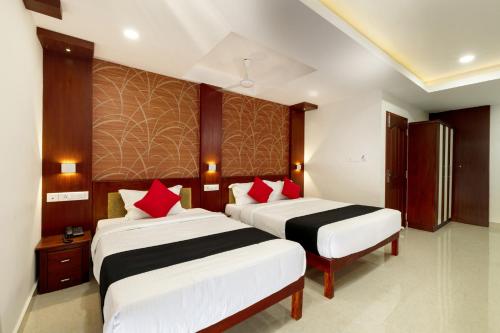 two beds in a hotel room with red pillows at Burooj Hotel in Cochin