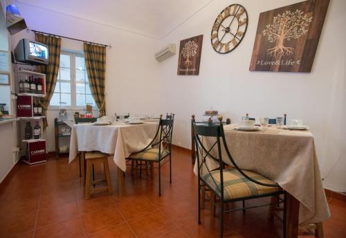 a dining room with two tables and a clock on the wall at Hospedaria Os Condes in Reguengos de Monsaraz