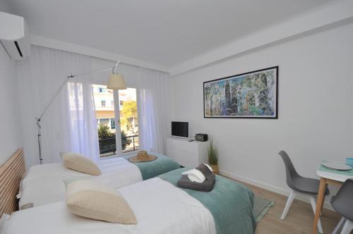 a room with two beds and a table and a window at 9 Rue Buttura in Cannes
