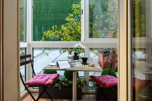 une table avec des chaises matelassées roses devant une fenêtre dans l'établissement Hôtel de la Tour Eiffel, à Paris