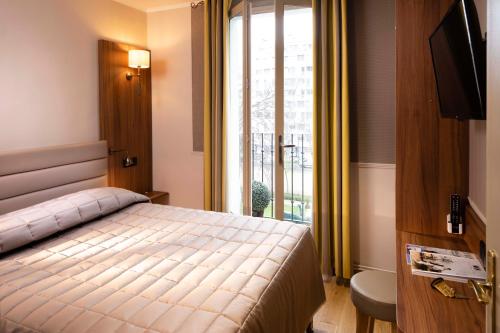une chambre avec un lit et une grande fenêtre dans l'établissement Hôtel de la Tour Eiffel, à Paris