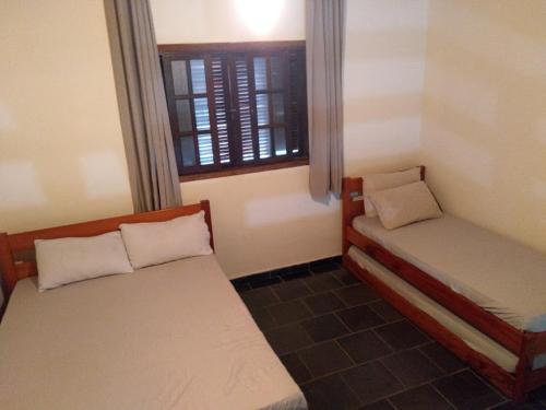 a small room with two beds and a window at Pousada Atobá Bertioga in Bertioga