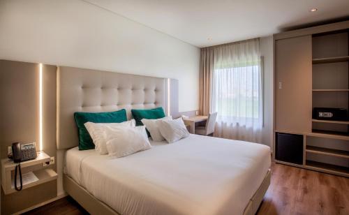 a bedroom with a large white bed with green accents at Oporto Airport & Business Hotel in Maia