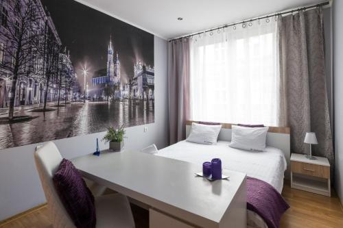 Schlafzimmer mit einem weißen Bett, einem Schreibtisch und einem Fenster in der Unterkunft JM Apartments zamieszkaj w Centrum in Krakau
