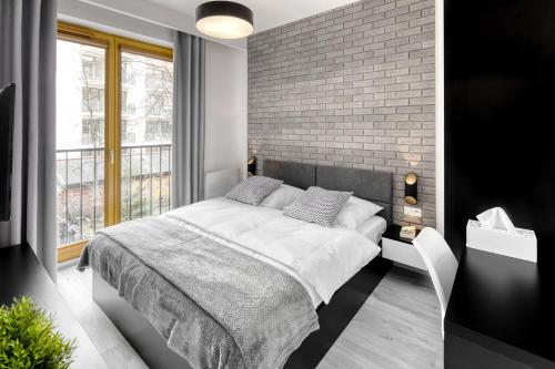 een slaapkamer met een bed en een bakstenen muur bij Native Apartments Lubelska 10 in Krakau