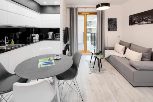 een keuken en een woonkamer met een tafel en een bank bij Native Apartments Lubelska 10 in Krakau