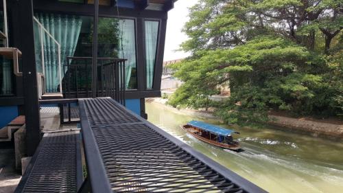 a boat traveling down a river with a building at Baan Mae Khian Cafe & Boutique Hotel in Phra Nakhon Si Ayutthaya