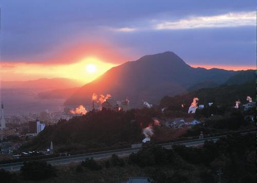 a view of a mountain with the sun setting at Resorpia Beppu in Beppu