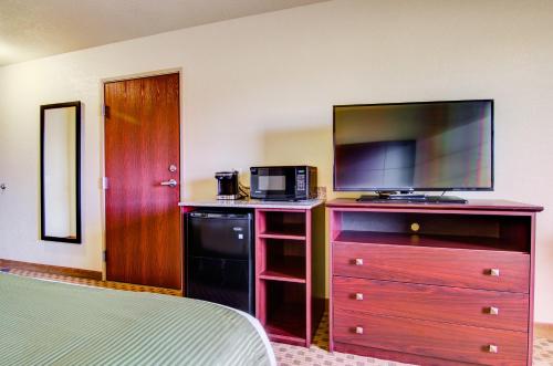 a bedroom with a tv on a dresser with a bed at Cobblestone Hotel & Suites Pulaski/Green Bay in Pulaski