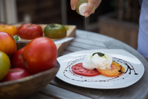 a person is sprinkling sauce on a plate of food at Bridgehampton Inn in Bridgehampton