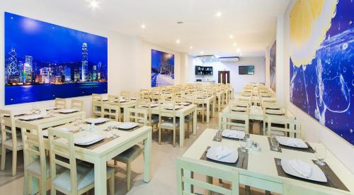 a restaurant with white tables and chairs and a large mural at Ribai Hotels -Riohacha in Ríohacha