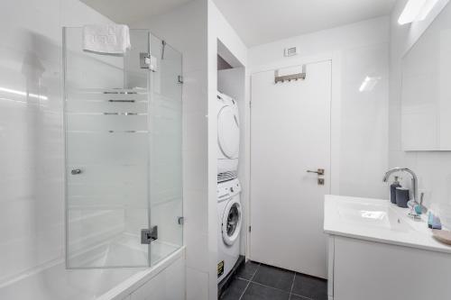een witte badkamer met een wasmachine en een wastafel bij Spacious & Design 2BDR W/ balcony and parking in Tel Aviv