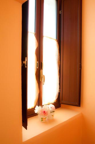 a window with two vases of flowers on a window sill at Il Giardino Del Sole in Agnone Bagni