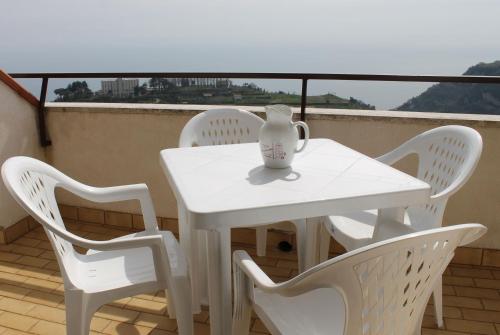 een witte tafel en stoelen op een balkon met een vaas erop bij Casa Radicosa in Agerola