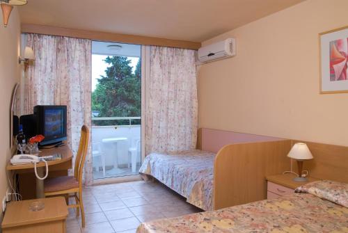 a hotel room with a bed and a desk and a window at Hotel Oasis in Albena
