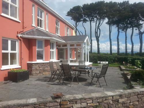 a patio with chairs and a table in front of a pink house at Eask View Dingle - Room Only in Dingle