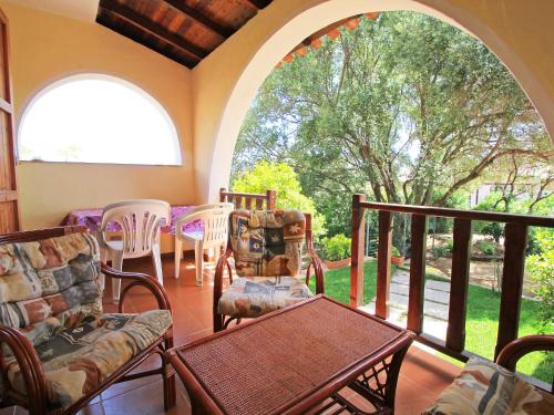 サンタ・マルゲリータ・ディ・プーラにあるHoliday Home Is Molas by Interhomeの椅子とテーブル付きのポーチ、アーチ型の窓