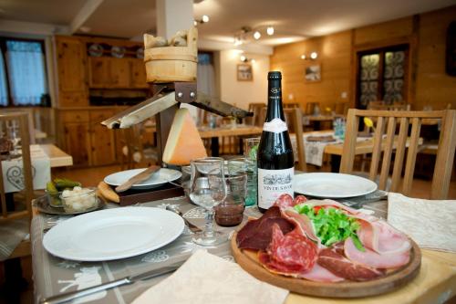 a table with a bottle of wine and a plate of meat at Chalet Hotel La Tarine in Peisey-Nancroix