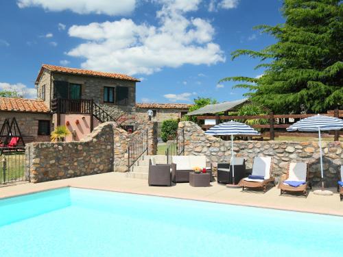 a pool with chairs and umbrellas and a house at Holiday Home La Fornace by Interhome in Roccastrada