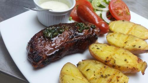 a plate with a steak and potatoes and a salad at Hotel La Algodonera in Ambato